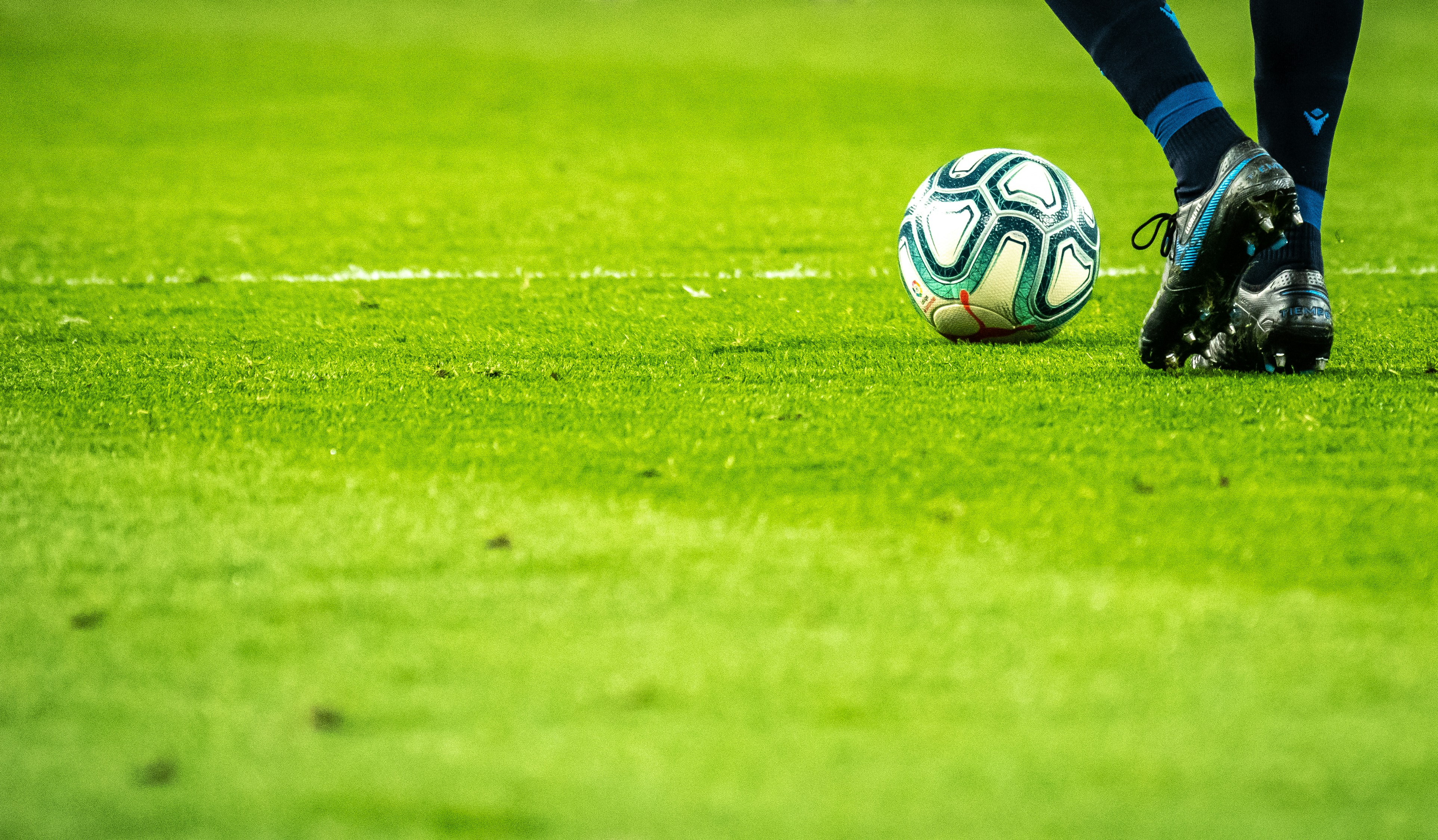 Bola de futebol ao lado de chuteira sobre gramado